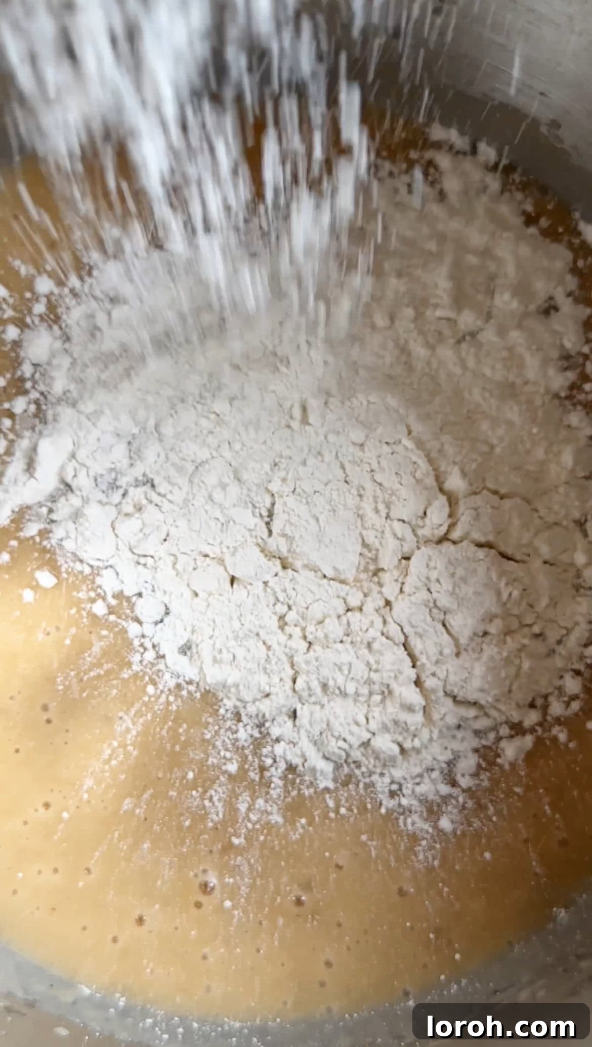 Gently stirring plain flour, bicarbonate of soda, and salt into the banana bread batter.