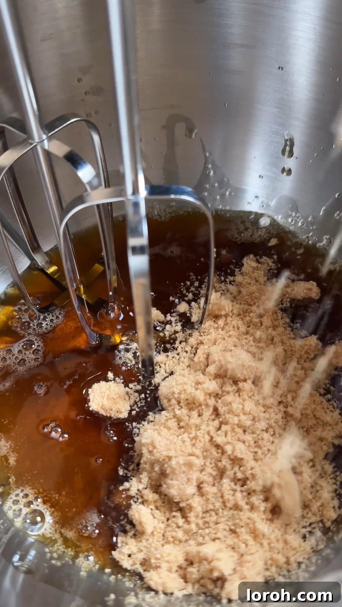Whisking brown butter with light brown and caster sugars in a mixing bowl.