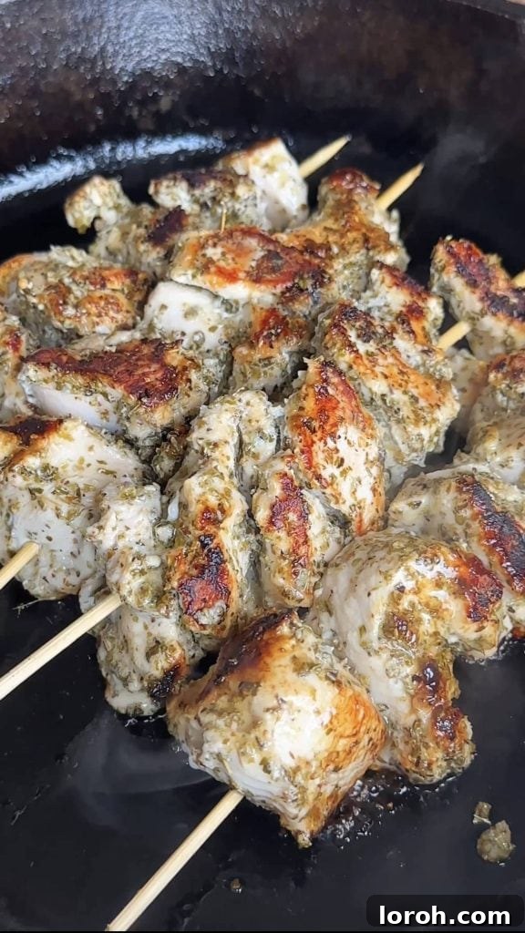 Grilling marinated chicken souvlaki skewers on a hot grill pan