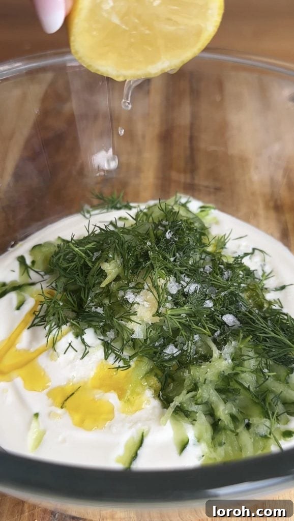 Ingredients for creamy tzatziki in a glass bowl, ready to be mixed