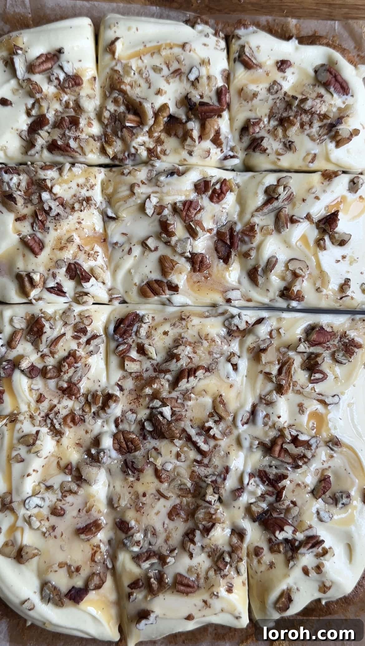 A perfectly baked carrot cake tray bake, covered with luscious cream cheese icing, with a knife poised for slicing.