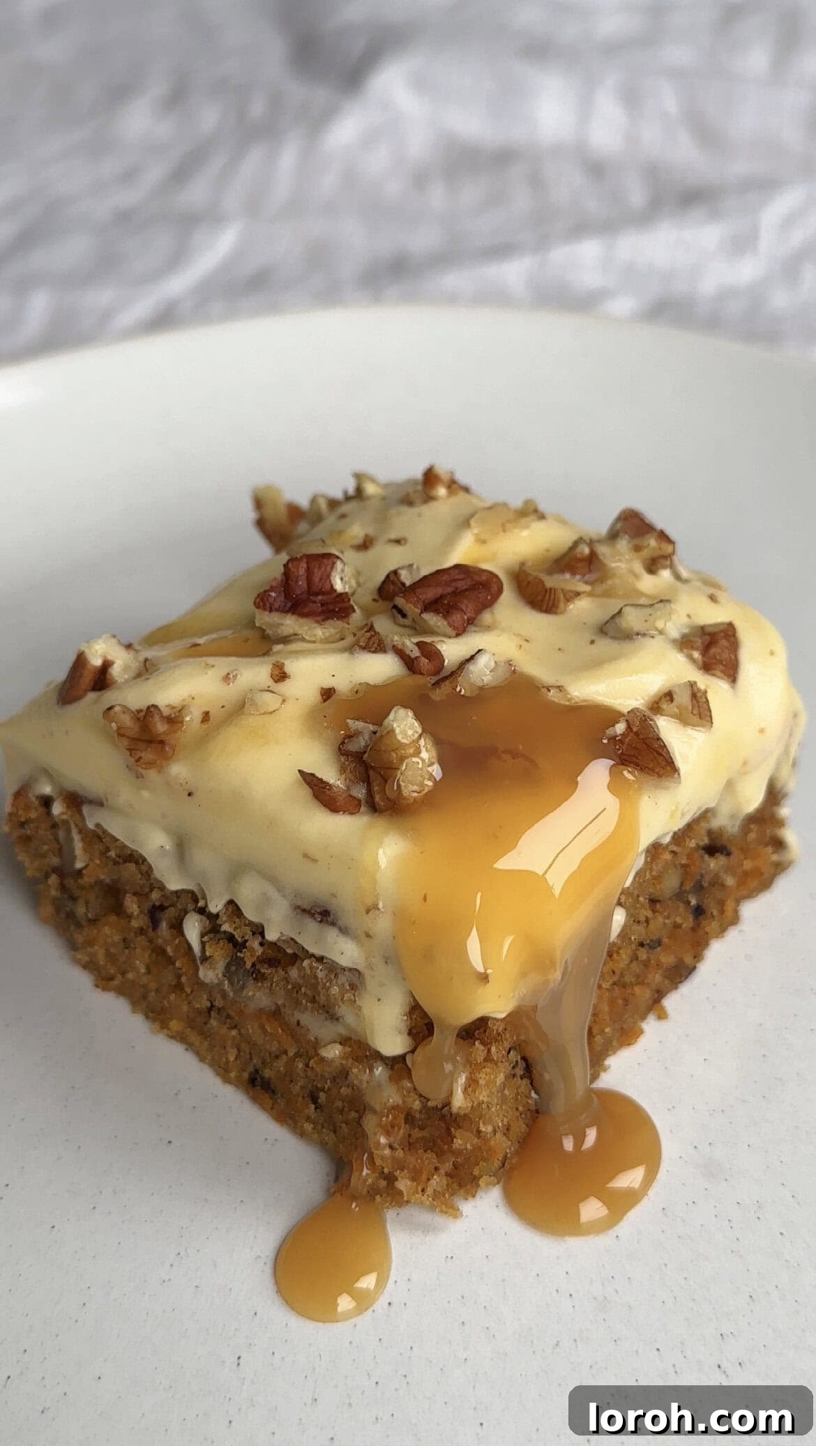 A perfectly portioned slice of carrot cake tray bake, beautifully presented on a white plate, ready to be enjoyed.