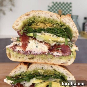 Stacked gourmet chicken bacon sandwich on a wooden board, ready to serve.