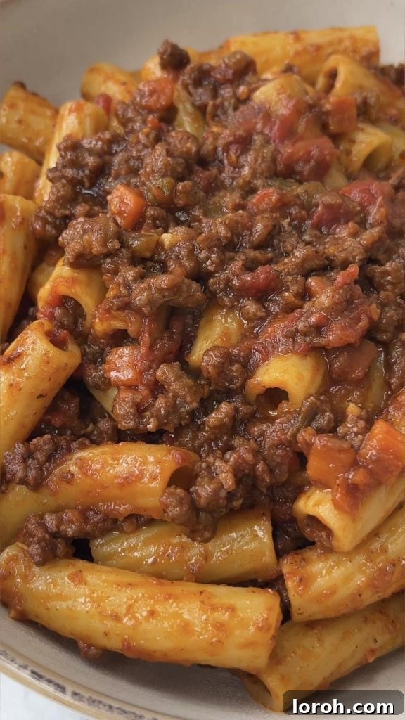 A close-up shot of perfectly cooked rigatoni pasta generously coated in a rich, quick Bolognese sauce.