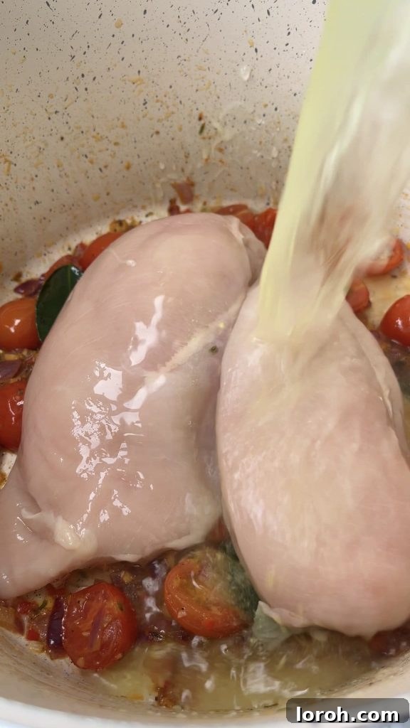 Aromatic Thai Chicken and Rice Soup with Bright Cherry Tomatoes 3 Adding chicken stock to a saucepan with chicken breasts and sautéed aromatics for Thai Chicken Soup.