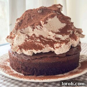 A magnificent chocolate mud cake generously topped with malted whipped cream, highlighting its inviting texture.