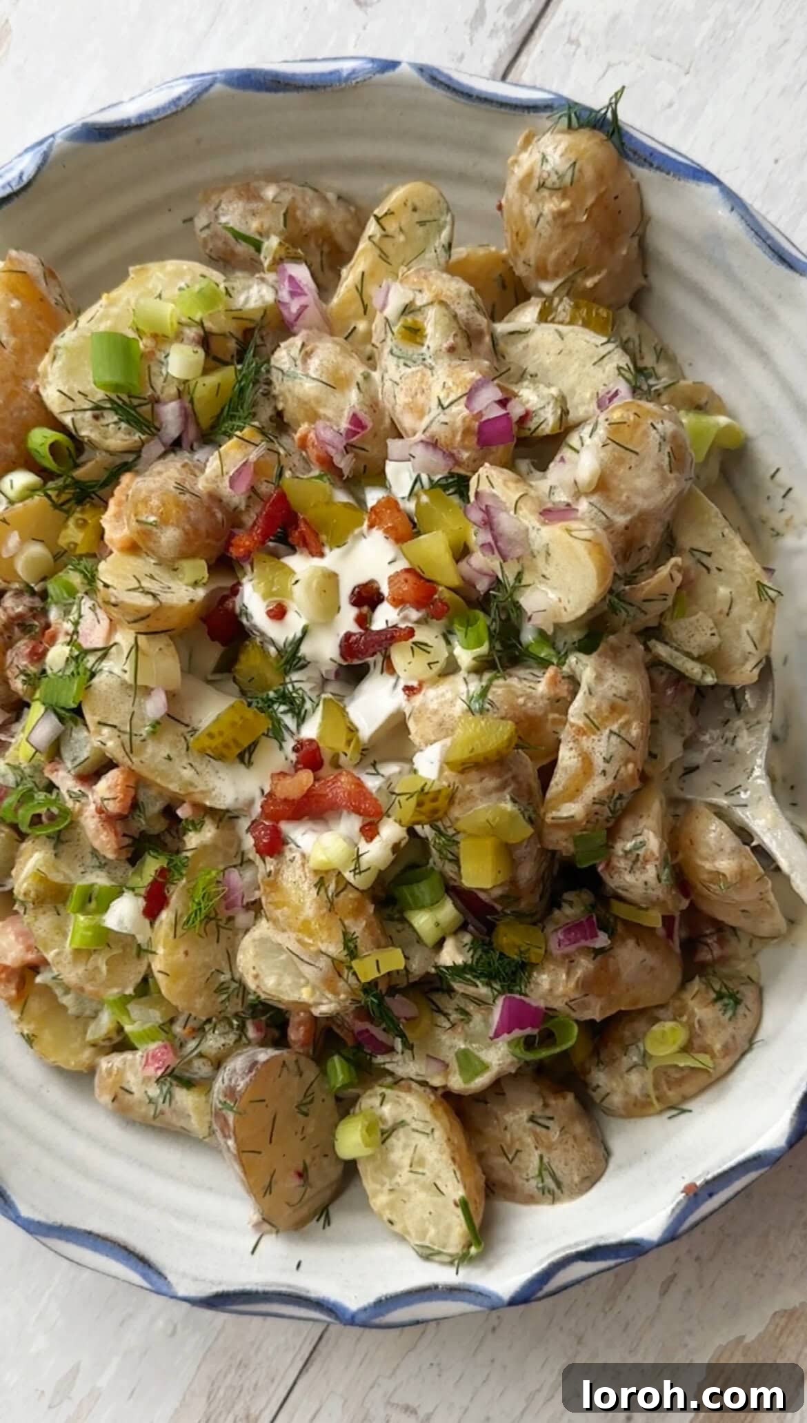Close-up of potato salad with dill and pickles, showing the creamy texture and fresh herbs.