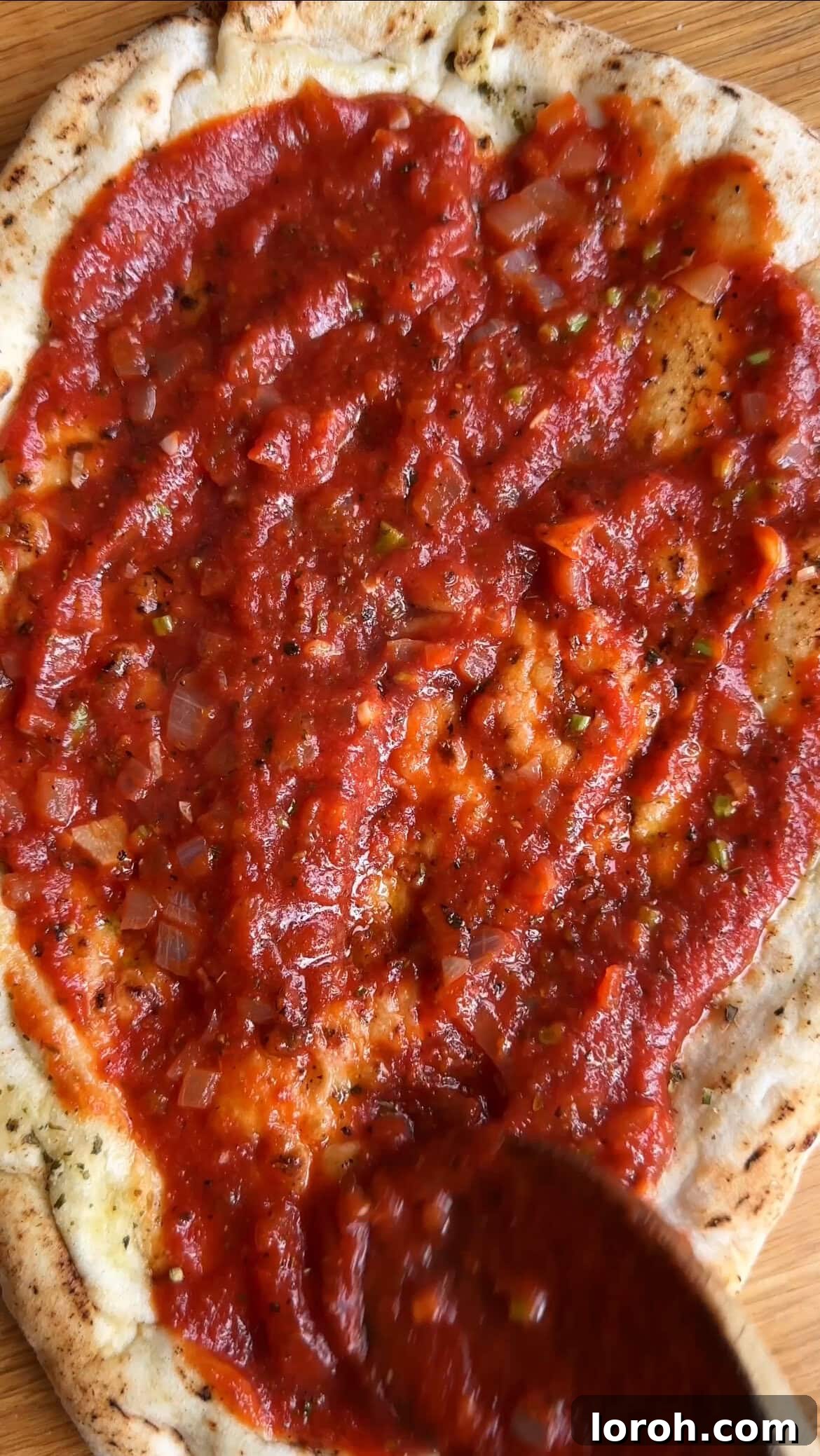 Margherita Flatbread Pizza 6 Spreading homemade tomato sauce evenly onto a prepared flatbread base.