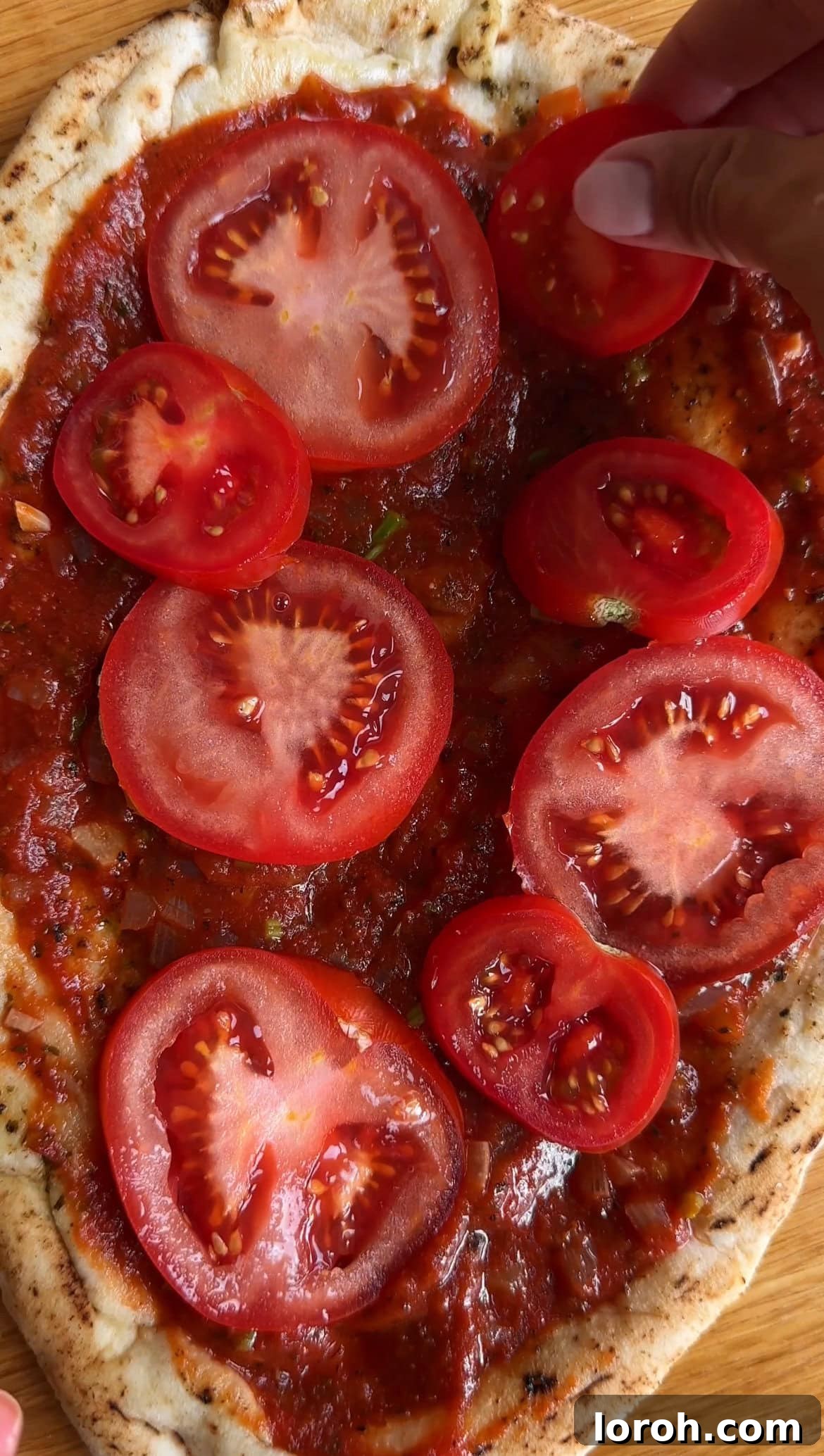 Margherita Flatbread Pizza 7 Arranging fresh tomato slices over the tomato-sauced flatbread base.
