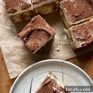 A slice of tiramisu tres leches cake on a plate with the full cake on the table