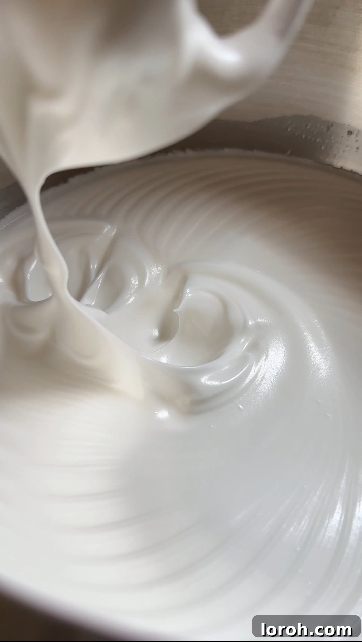 Whisked egg whites forming stiff peaks in a mixing bowl, ready for the cake batter.