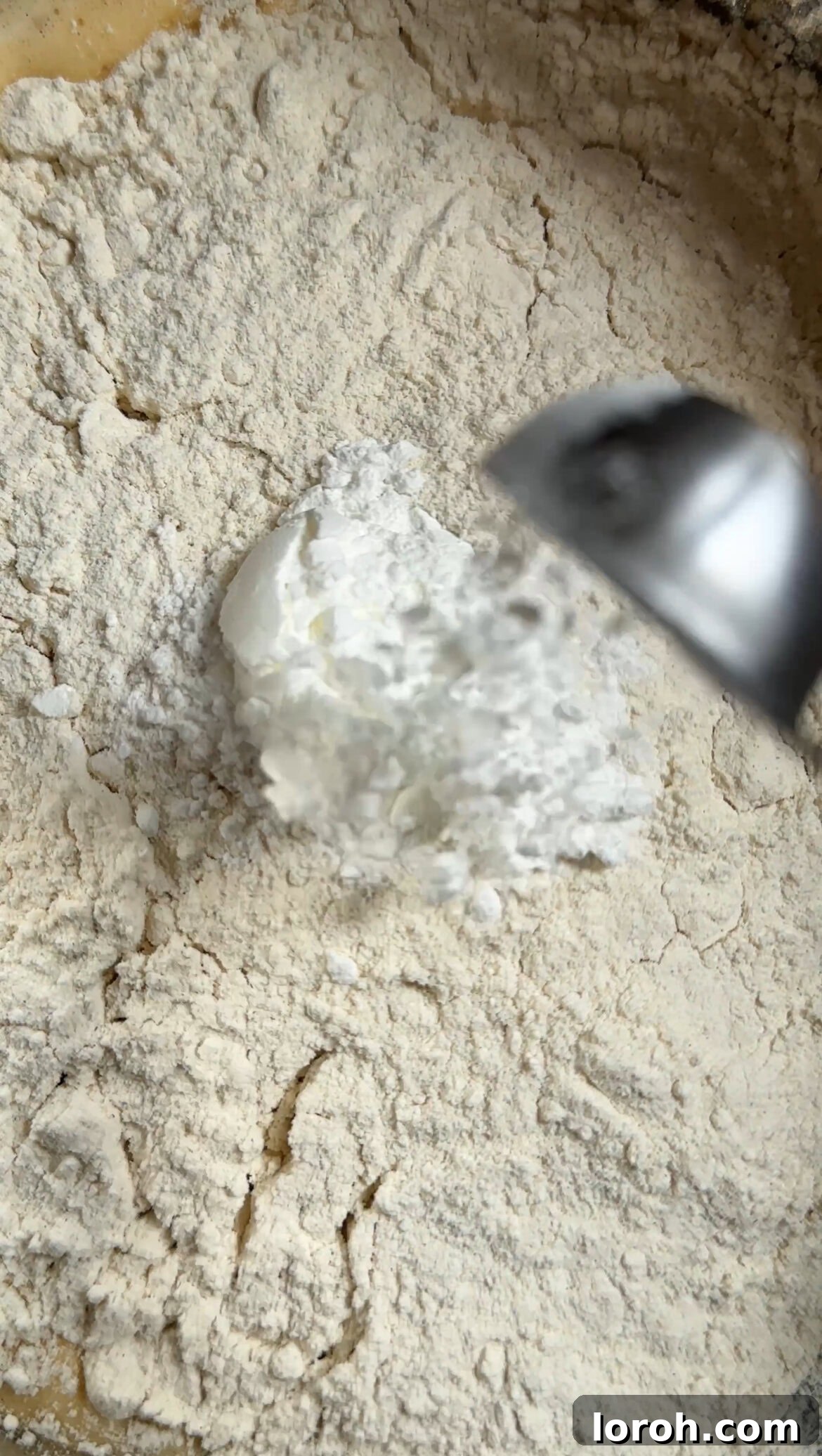 Sifting plain flour, baking powder, and salt into the wet ingredients for the tiramisu tres leches cake.
