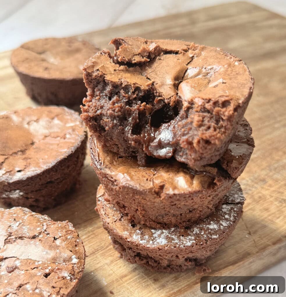 Brownie Nibbles 2 A charming stack of fudgy brownie bites artfully arranged on a rustic wooden chopping board, highlighting their perfect size and texture.