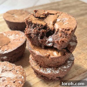 A stack of delightful brownie bites expertly arranged on a wooden chopping board, showcasing their inviting texture.