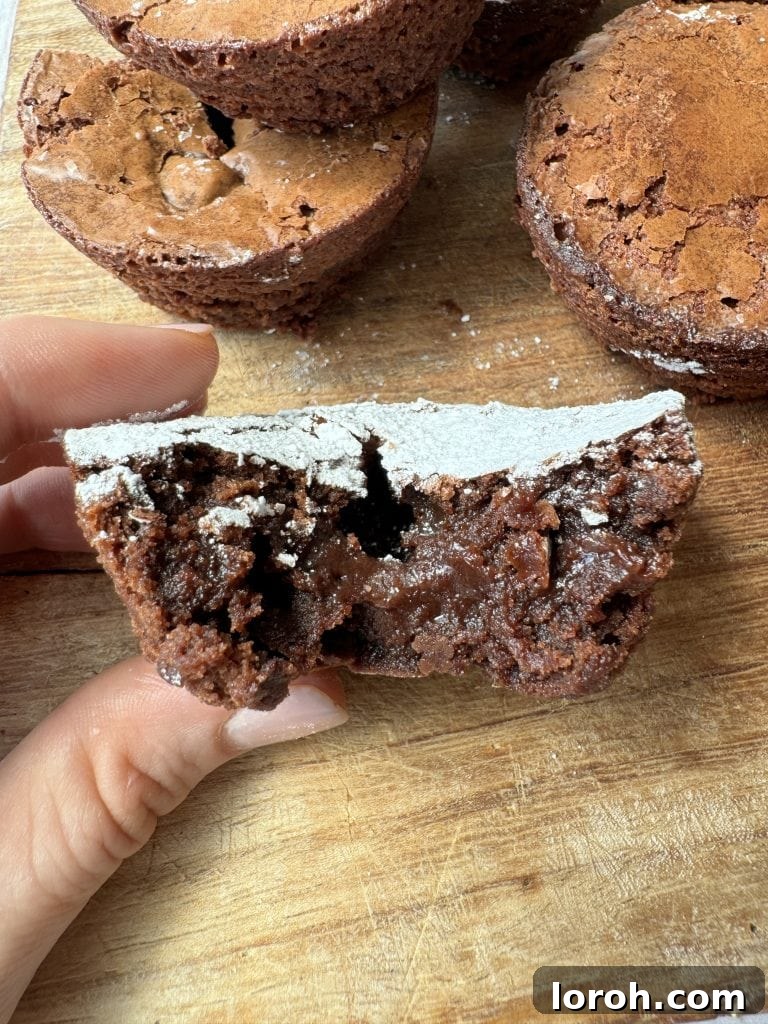 Brownie Nibbles 3 A woman's hand delicately holding half a perfectly fudgy brownie bite, showcasing its rich, dense interior.