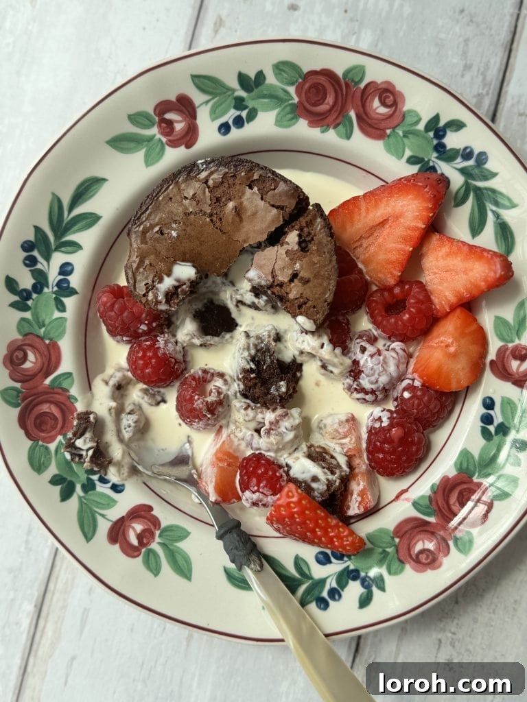 Brownie Nibbles 4 A single fudgy brownie bite nestled in a charming floral bowl, elegantly served with a dollop of cream and fresh berries.