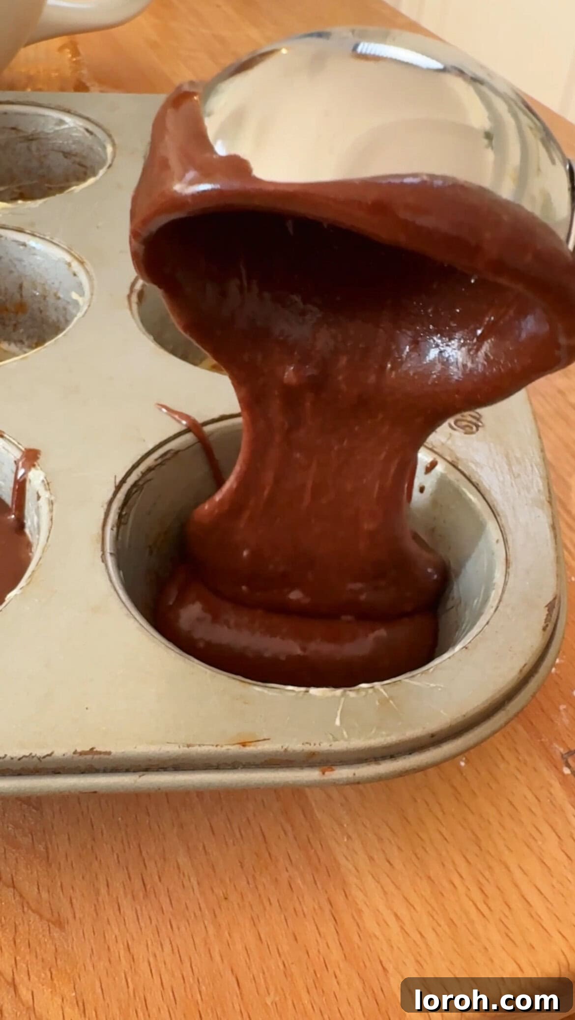 Brownie Nibbles 9 Step five: Brownie batter being scooped into a greased muffin tin using an ice cream scoop, ready for baking.