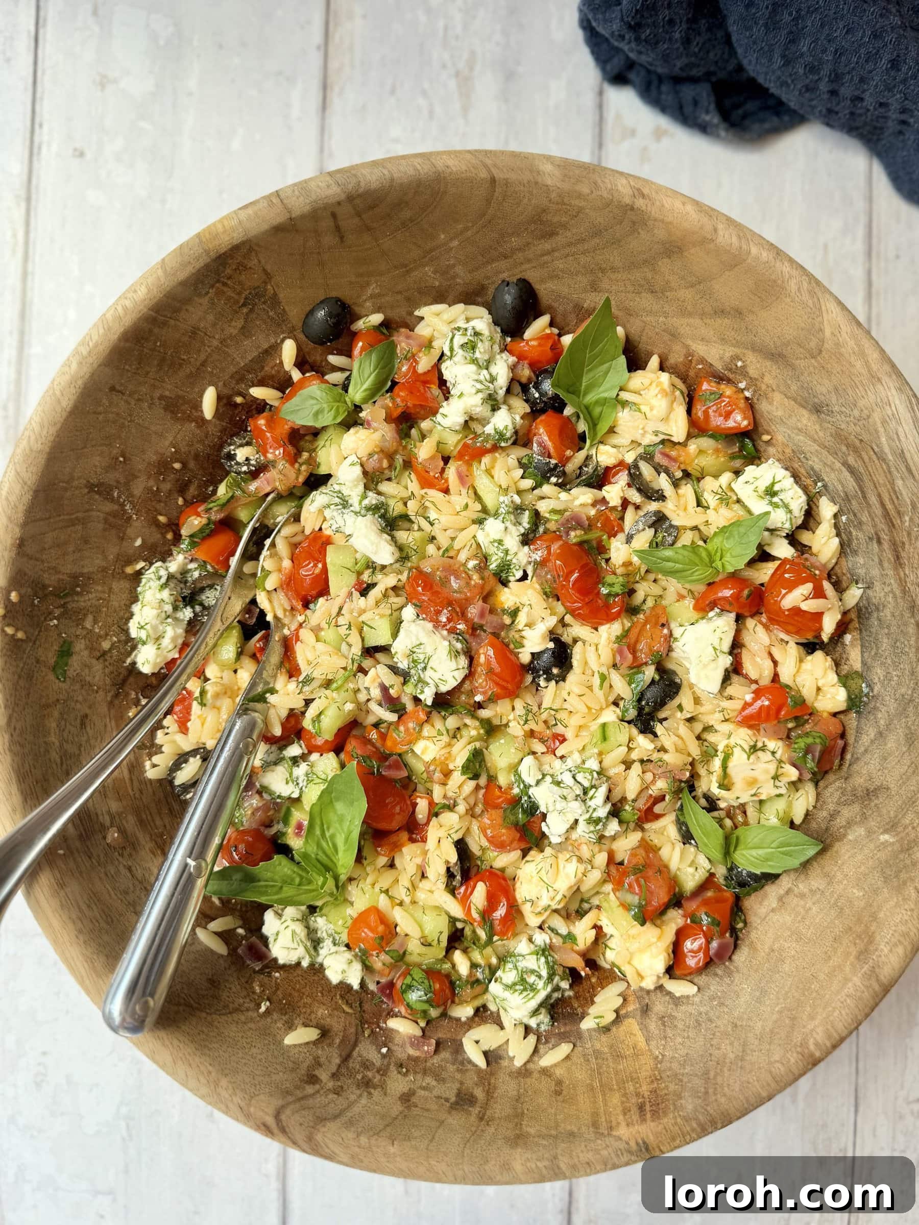 Vibrant Greek Orzo Salad 3 Overhead shot of a Greek pasta salad with orzo in a rustic wooden bowl, showcasing vibrant colors and textures.