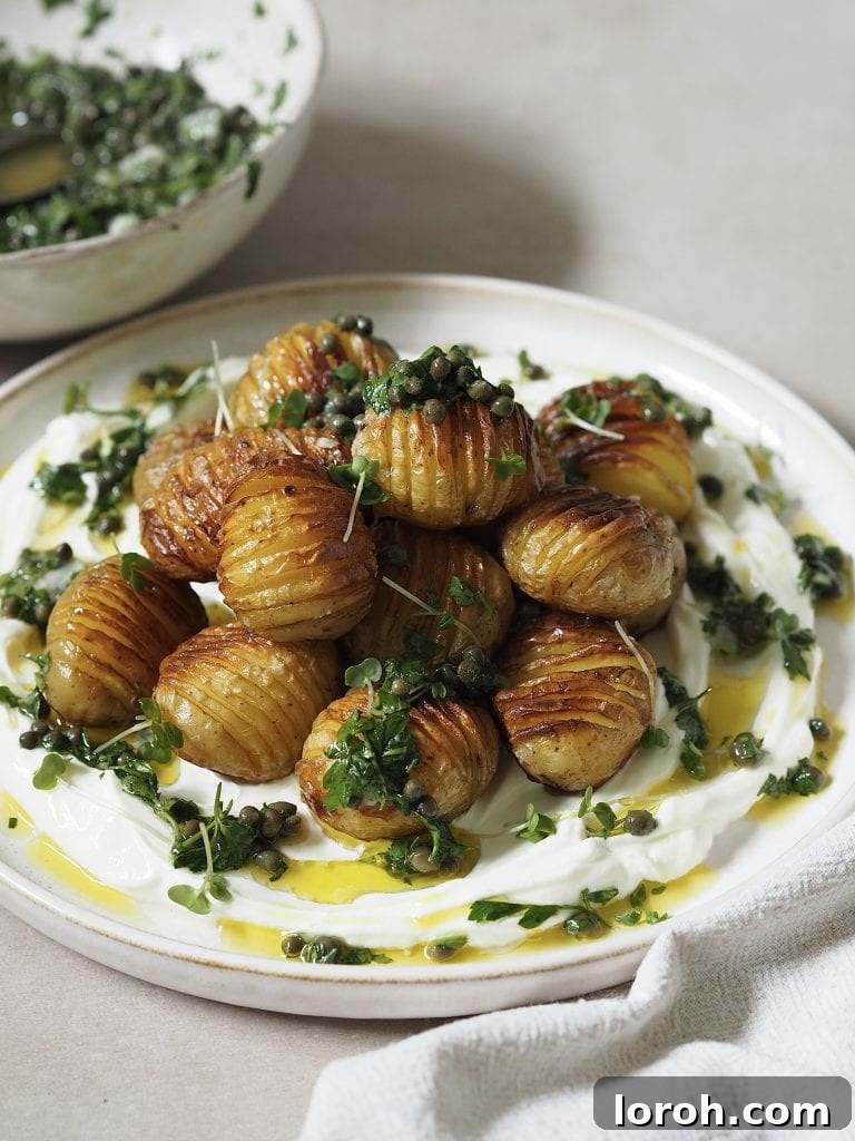 Golden Hasselback with Vibrant Salsa Verde & Tangy Labneh 10 A beautifully plated dish of labneh topped with golden hasselback potatoes, drizzled with salsa verde, and garnished with microgreens.