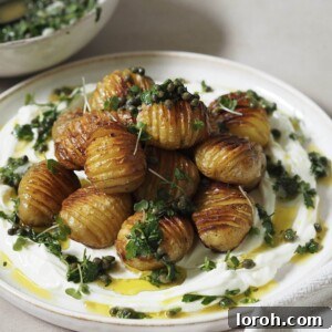 Golden Hasselback with Vibrant Salsa Verde & Tangy Labneh 11 A beautifully plated dish featuring creamy labneh topped with golden hasselback potatoes, vibrant salsa verde, and delicate microgreens.