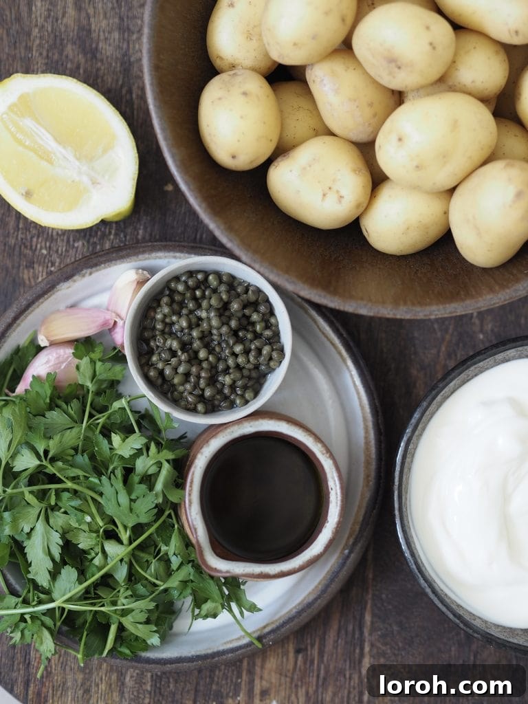 Golden Hasselback with Vibrant Salsa Verde & Tangy Labneh 3 A selection of fresh ingredients including baby potatoes, capers, parsley, lemons, and garlic, ready to prepare hasselback potatoes, salsa verde, and labneh.