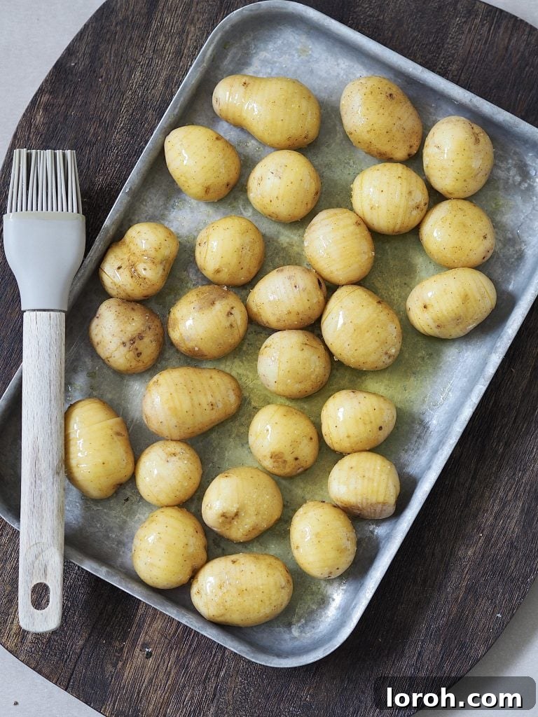 Golden Hasselback with Vibrant Salsa Verde & Tangy Labneh 5 Uncooked hasselback potatoes on a baking tray, ready for roasting.
