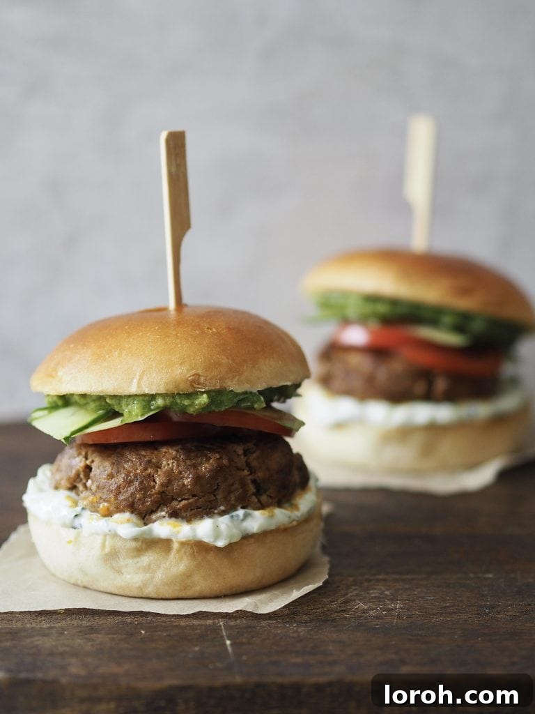 Lamb Burgers: A Fresh Mediterranean-Italian Blend 3 Two cooked lamb burgers on a wooden worktop.
