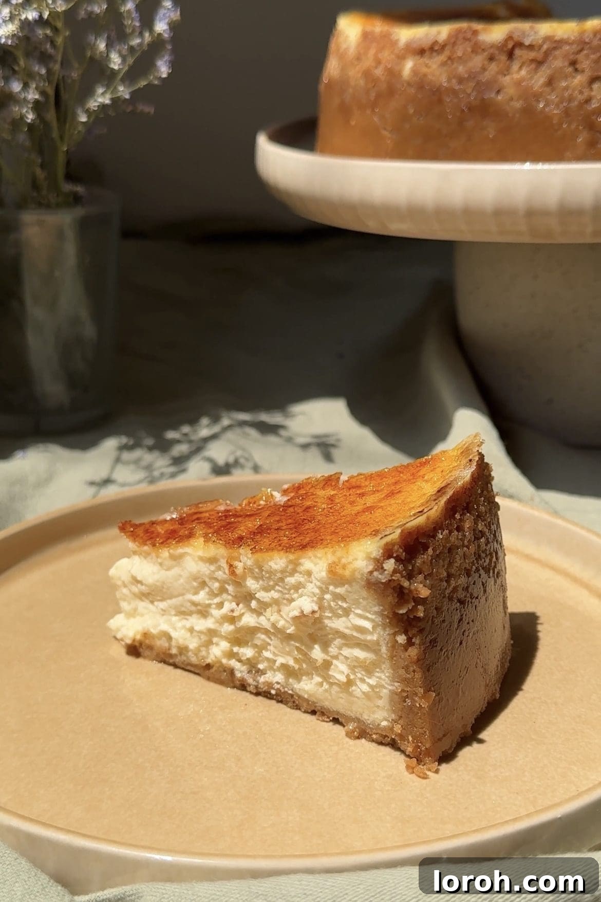 Golden Torched Cheesecake 14 A pristine slice of Crème Brûlée Cheesecake on a white plate, showcasing the distinct layers and crunchy topping.