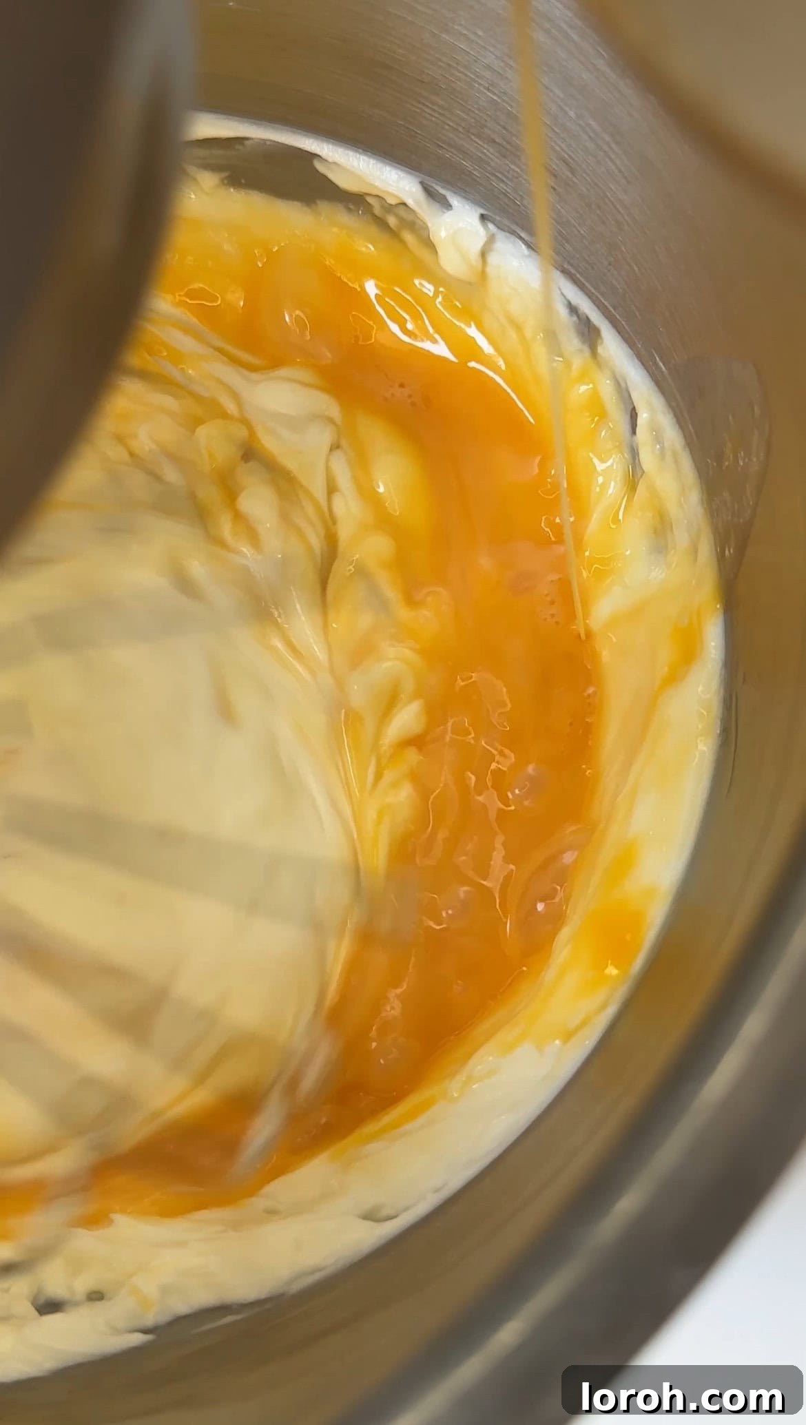 Golden Torched Cheesecake 9 Slowly adding lightly beaten eggs to the cheesecake batter in a mixer.