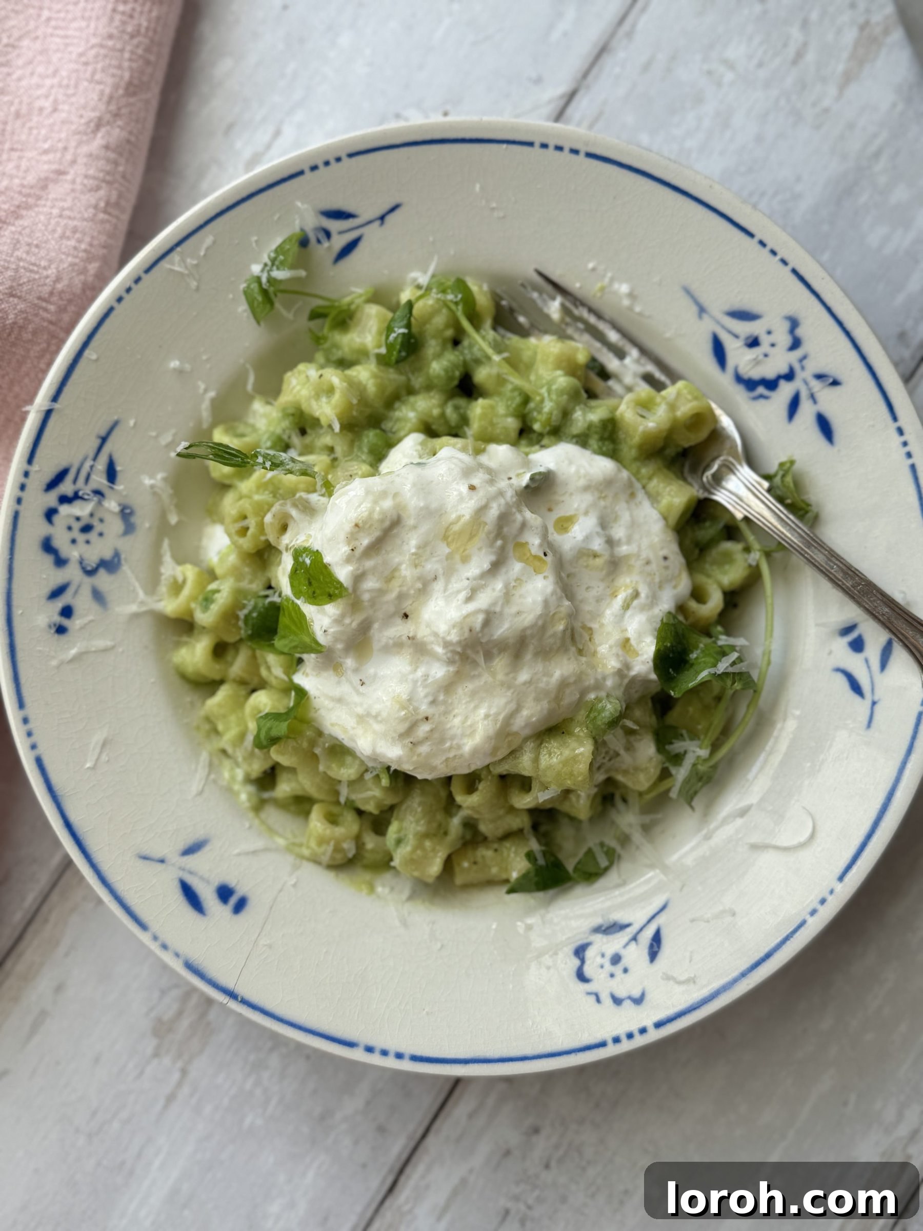 Close-up of one pan pasta and peas in a bowl with creamy burrata on top.