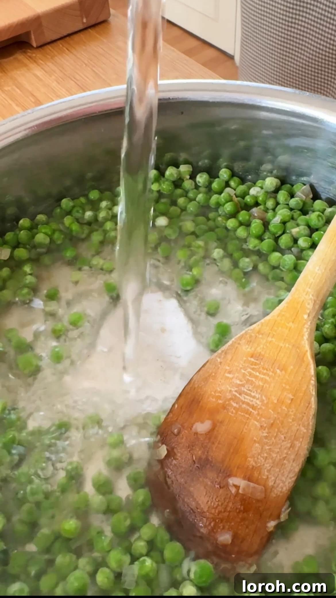 Adding water to the sautéed onions and peas in a frying pan.