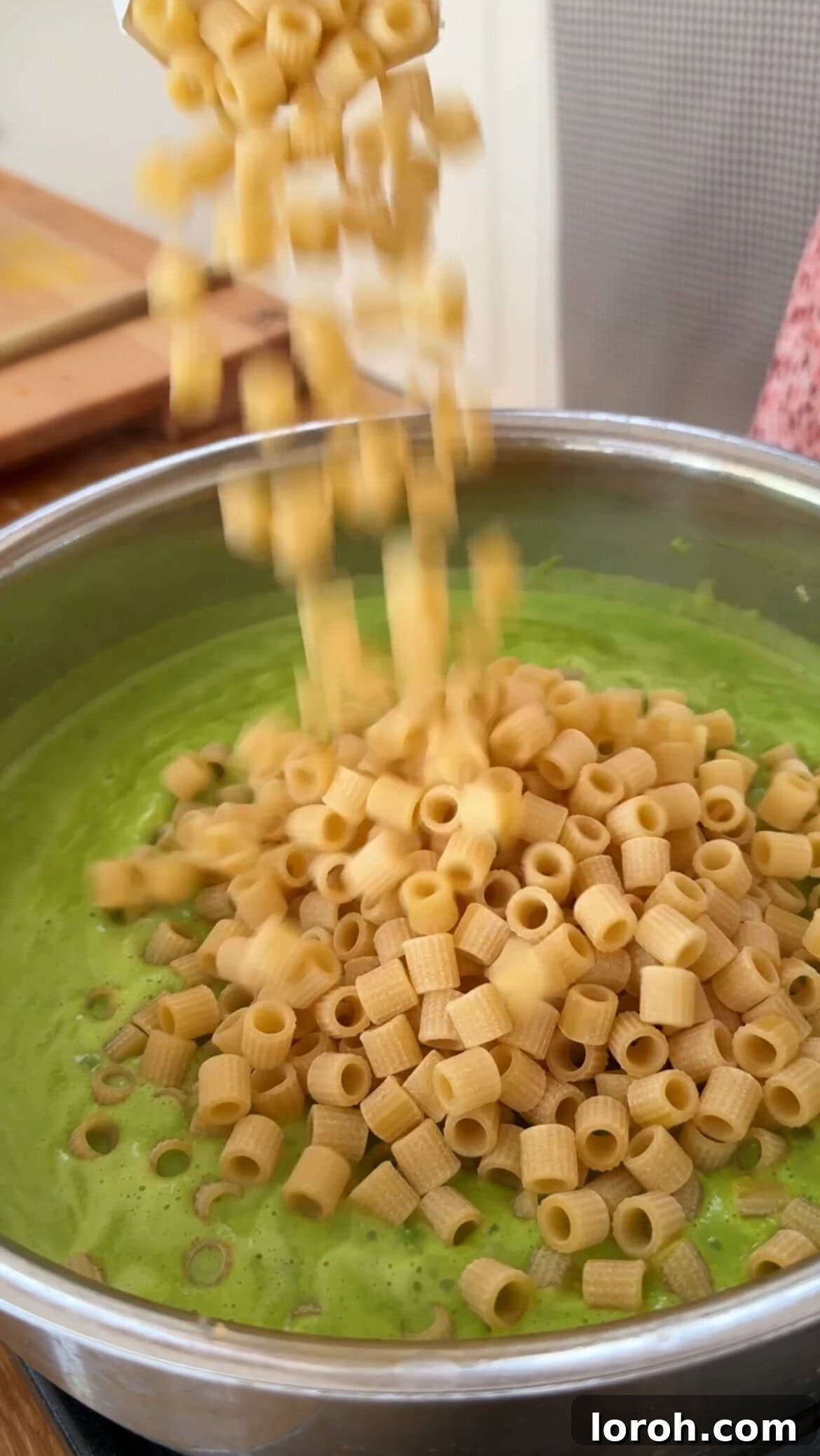 Adding uncooked pasta directly into the boiling pea sauce in the pan.