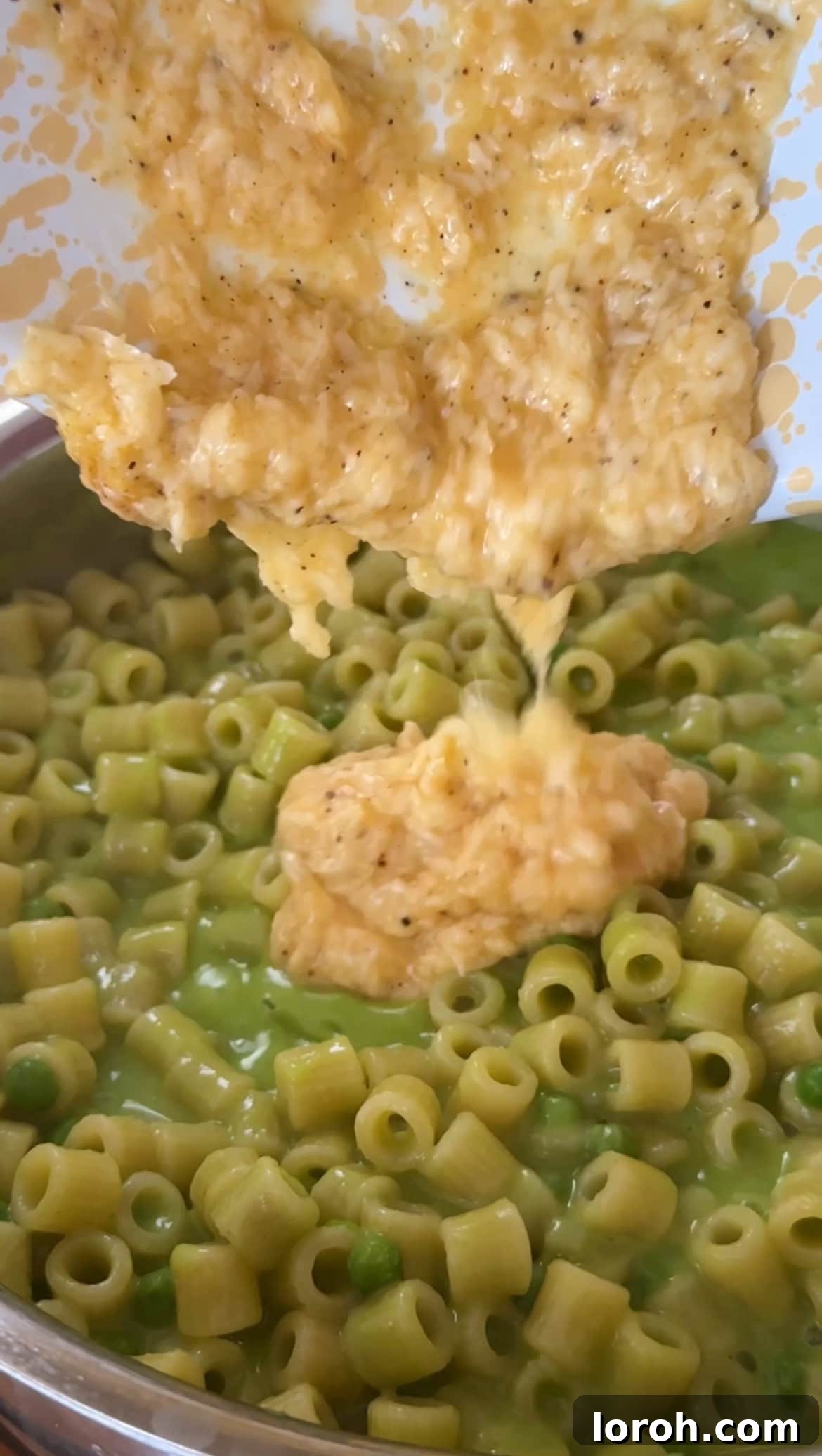 Mixing the whisked egg and Parmesan cheese into the cooked pasta.