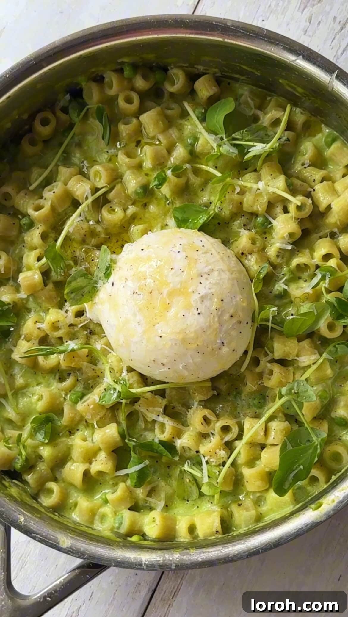 Garnishing the finished one pan pasta and peas with burrata and fresh basil.