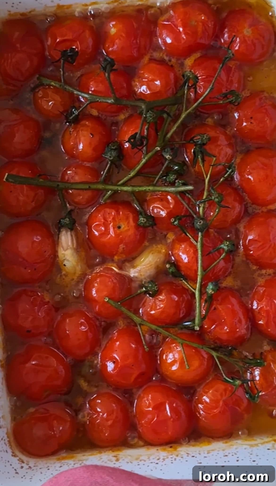 Tomato Butter: The Secret to Everything Delicious 5 Close-up of roasted cherry tomatoes and garlic in an ovenproof dish, glistening and softened after roasting.