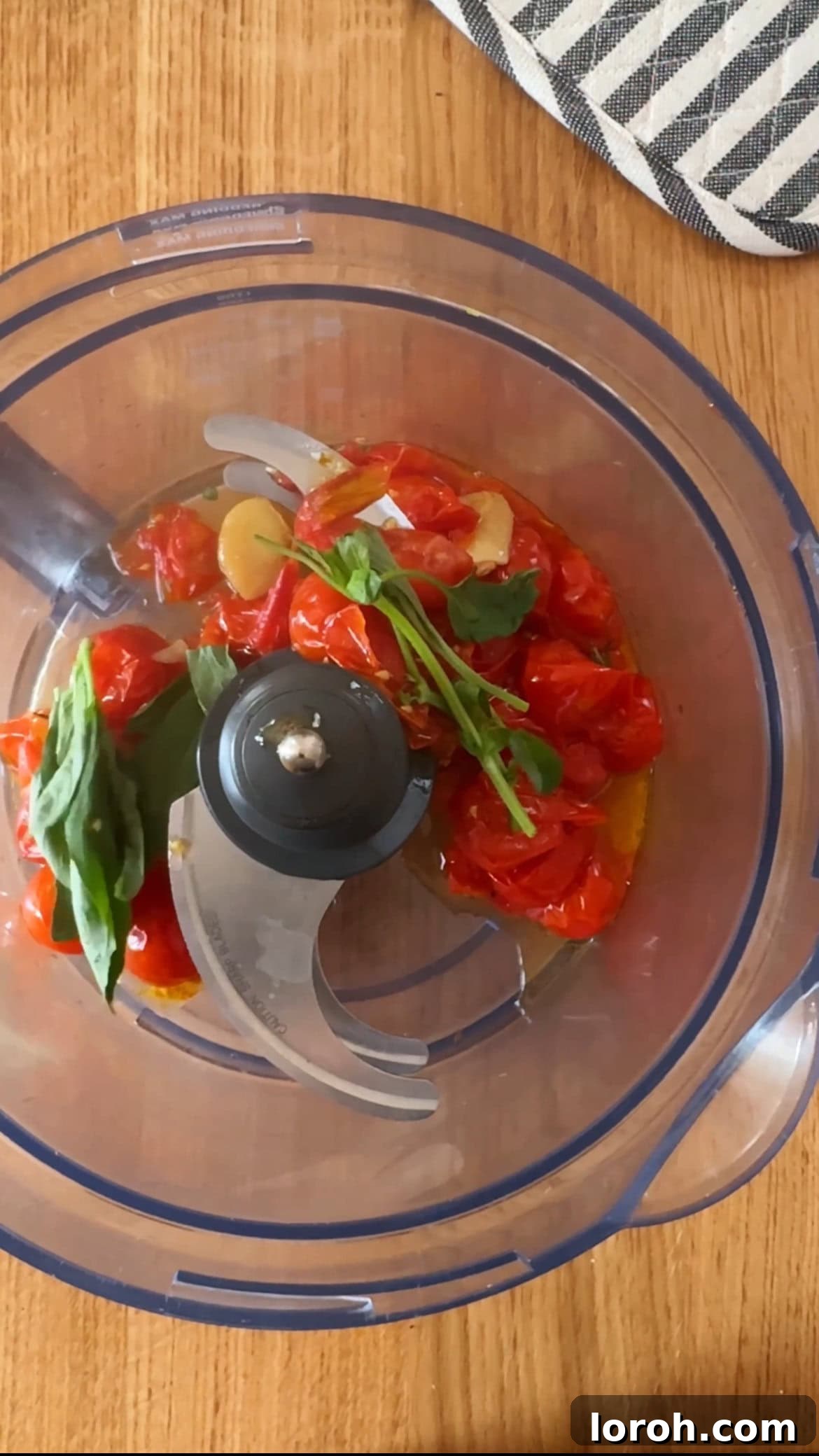 Tomato Butter: The Secret to Everything Delicious 6 Roasted tomatoes, peeled garlic, and fresh basil leaves inside a food processor, ready for blending.