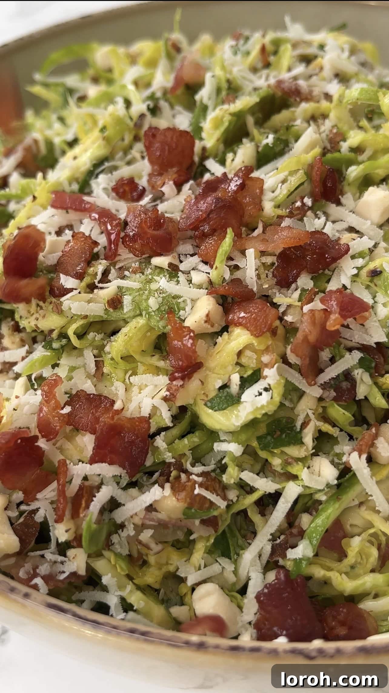 Close-up of a bowl of shaved Brussel sprout salad, highlighting the textures and ingredients