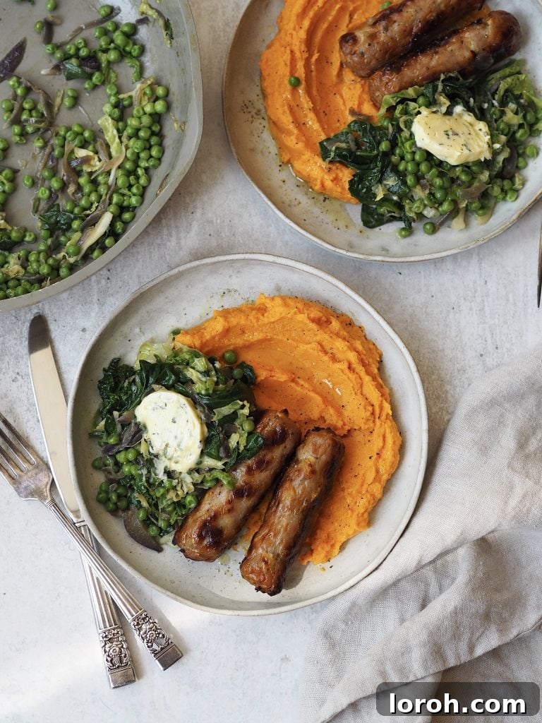 Grey plates of sweet potato mash, sausages and greens topped with a disc of garlic butter. 