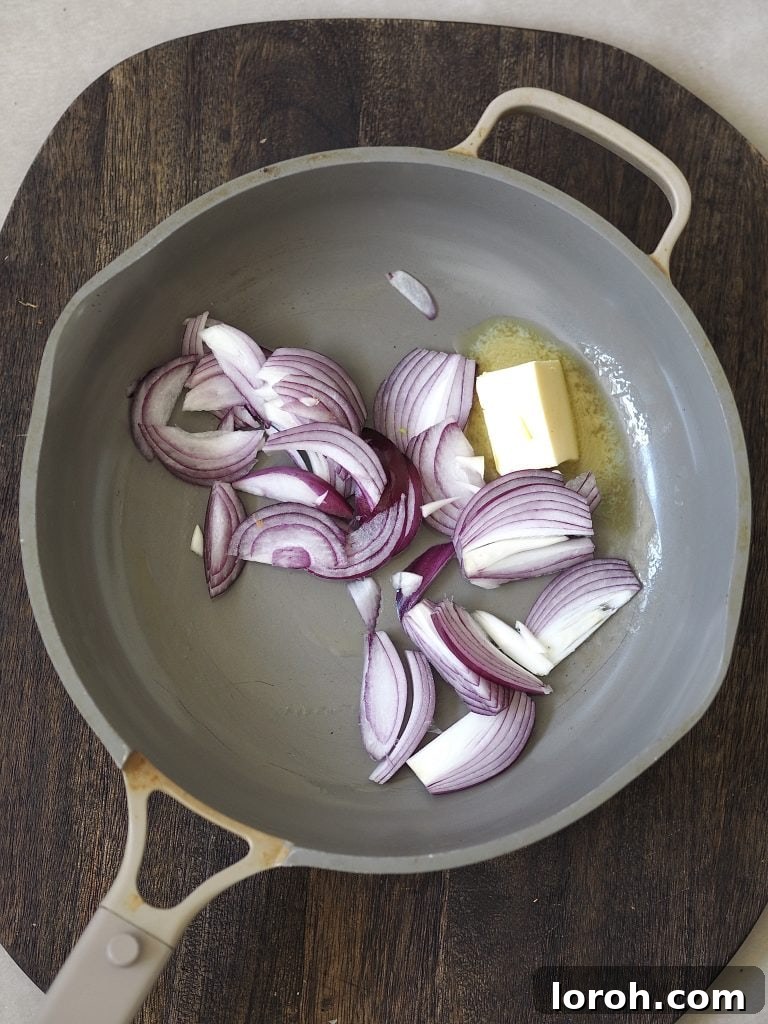 Raw red onions and butter in a frying pan.