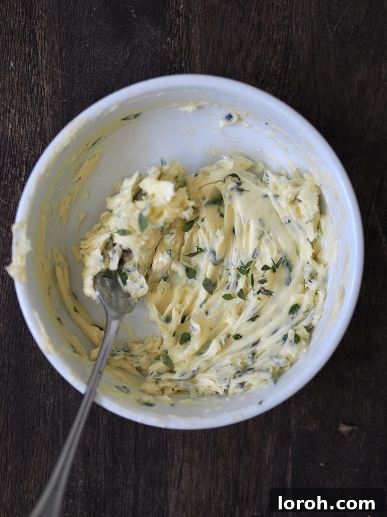 Garlic and thyme being beaten into soft butter with a fork.