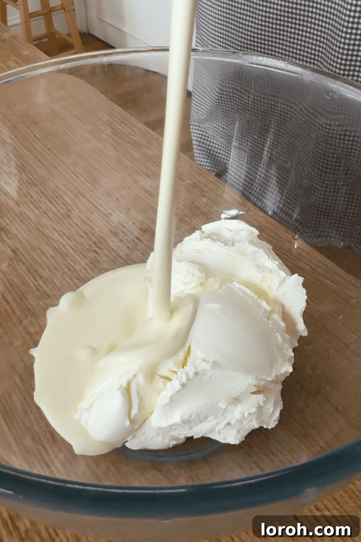 Whisking double cream and mascarpone cheese together in a bowl until the mixture becomes thick and combined.
