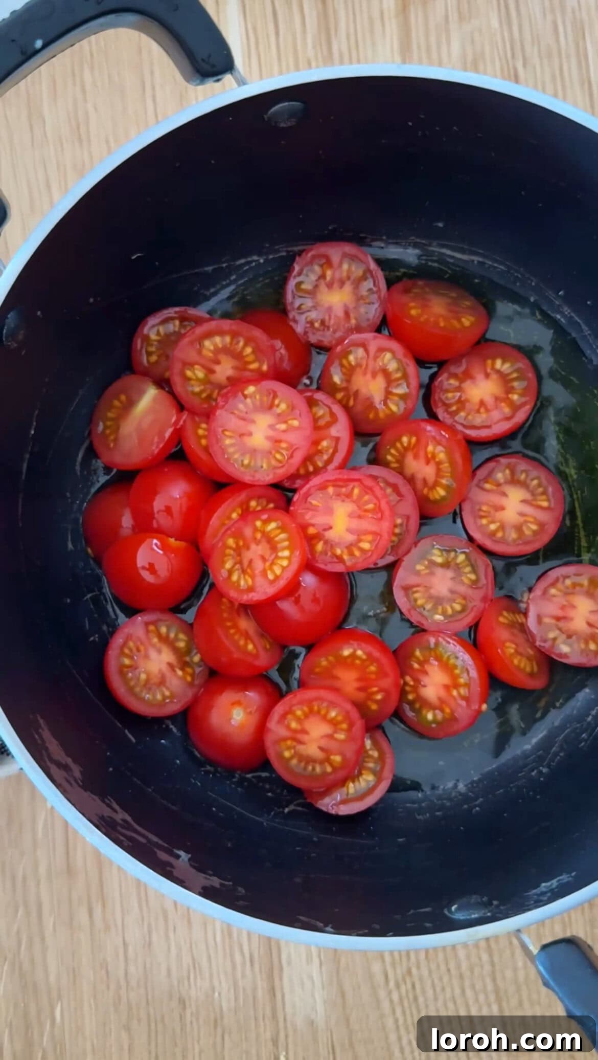 Cherry tomatoes gently frying in olive oil in a saucepan.