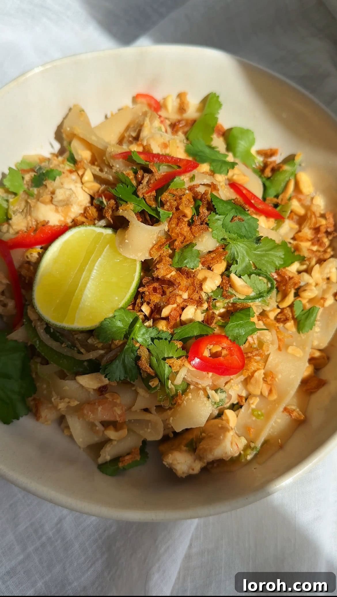 Wagamama Pad Thai served in a rustic stone bowl, garnished with fresh herbs and lime wedges.