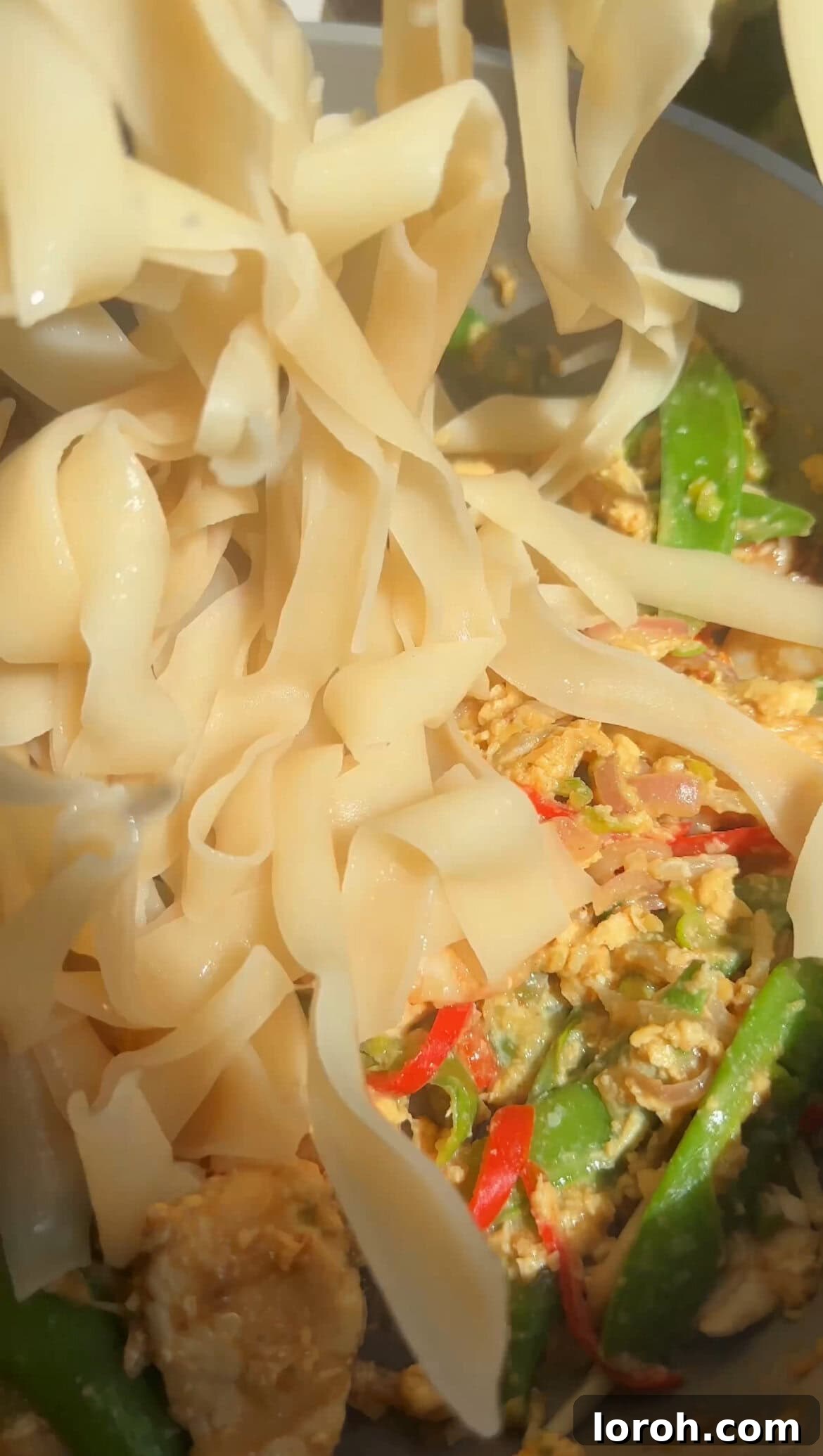 Adding cooked rice noodles to the Pad Thai mixture in a wok.