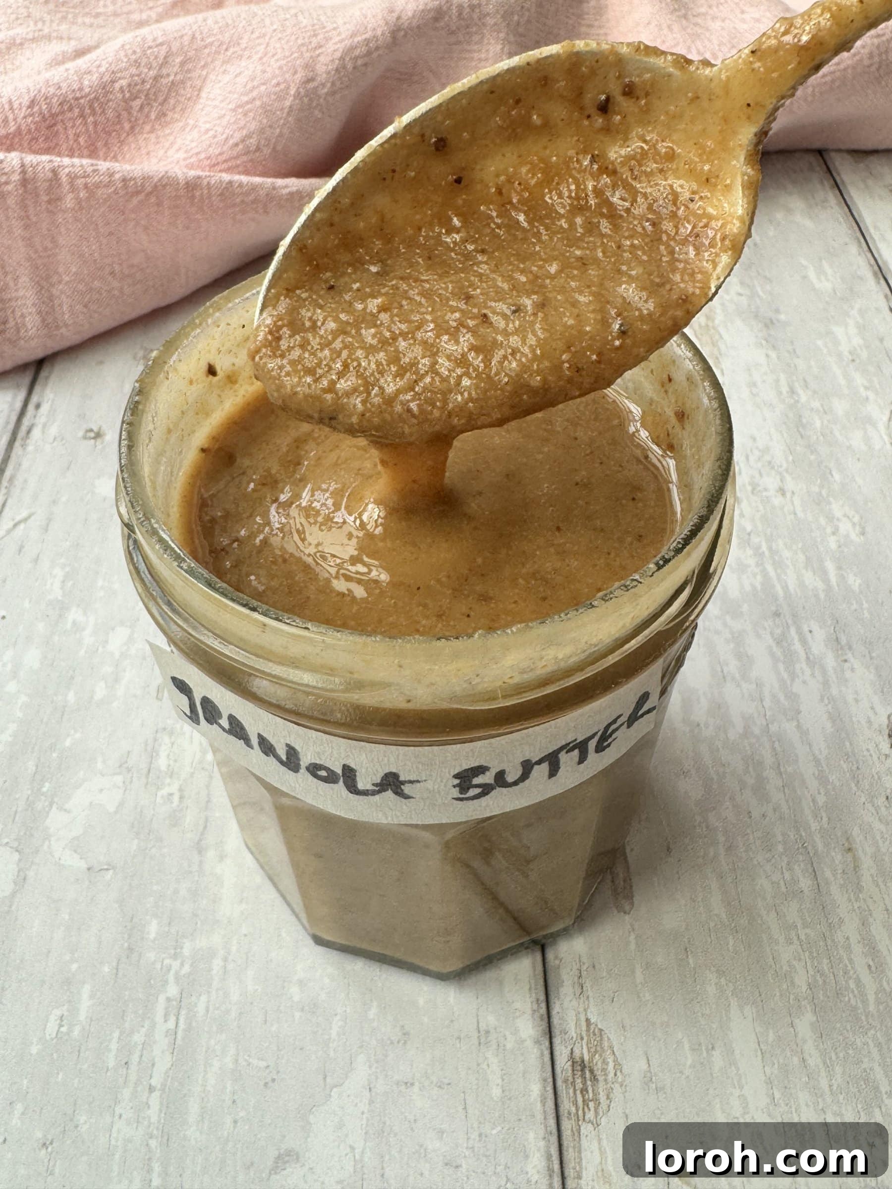 A jar of golden granola butter with a spoon, ready to be enjoyed.