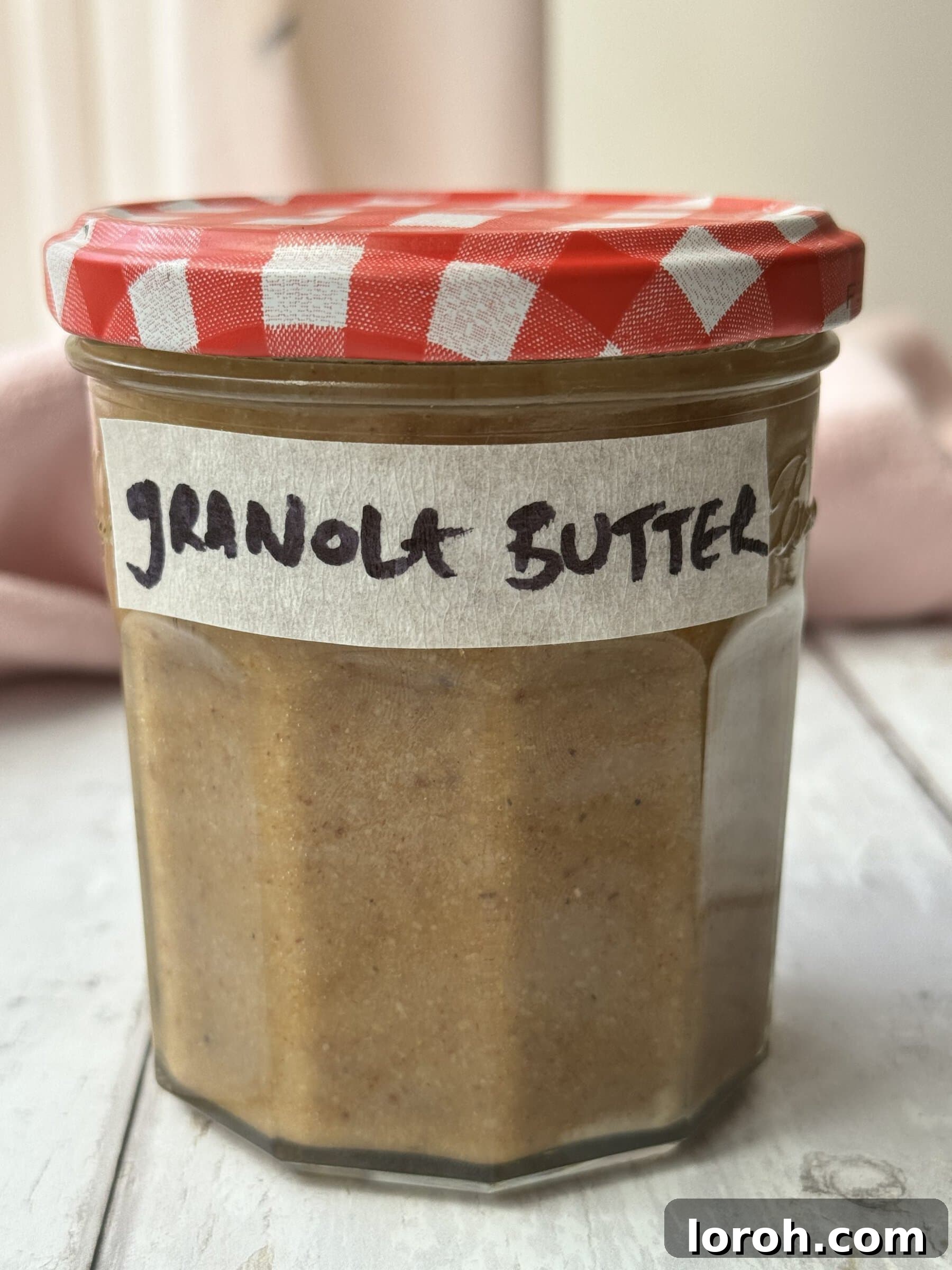 A charming jar of granola butter with a gingham lid and a custom label.