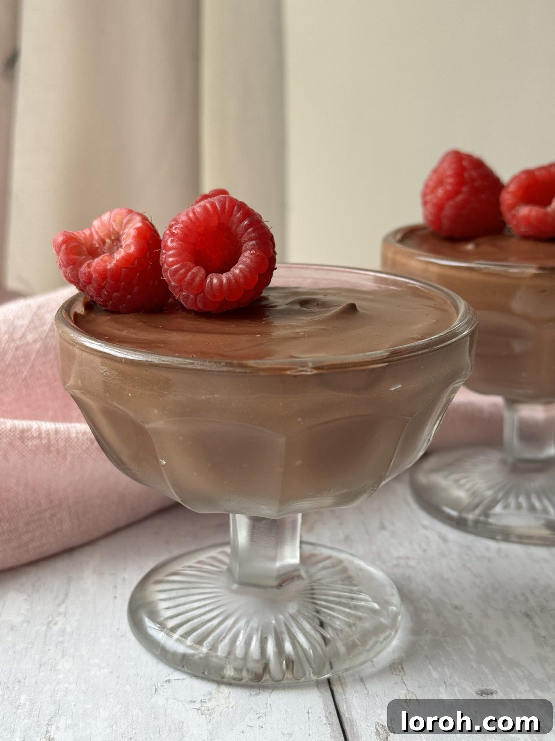 Velvety Protein Chocolate Mousse 3 chocolate protein mousse in a glass coupe with raspberries on top
