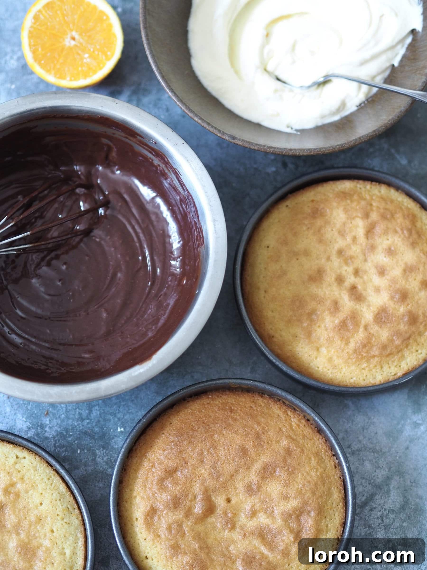 Various components for assembling the Jaffa Cake Cake: cooled sponge layers, marmalade buttercream, and chocolate ganache.