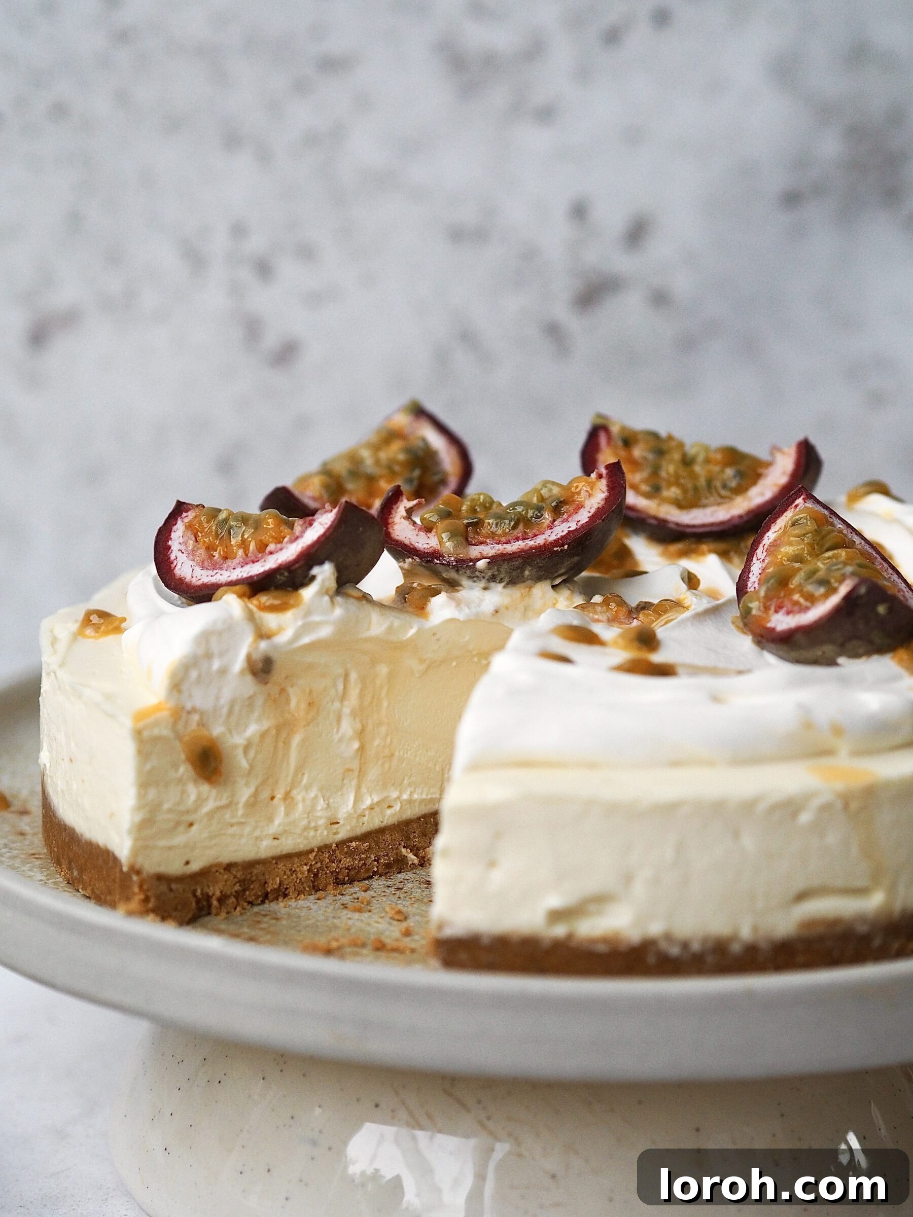 An overhead view of a whole White Chocolate and Passion Fruit Cheesecake with one slice elegantly removed, revealing its creamy texture.