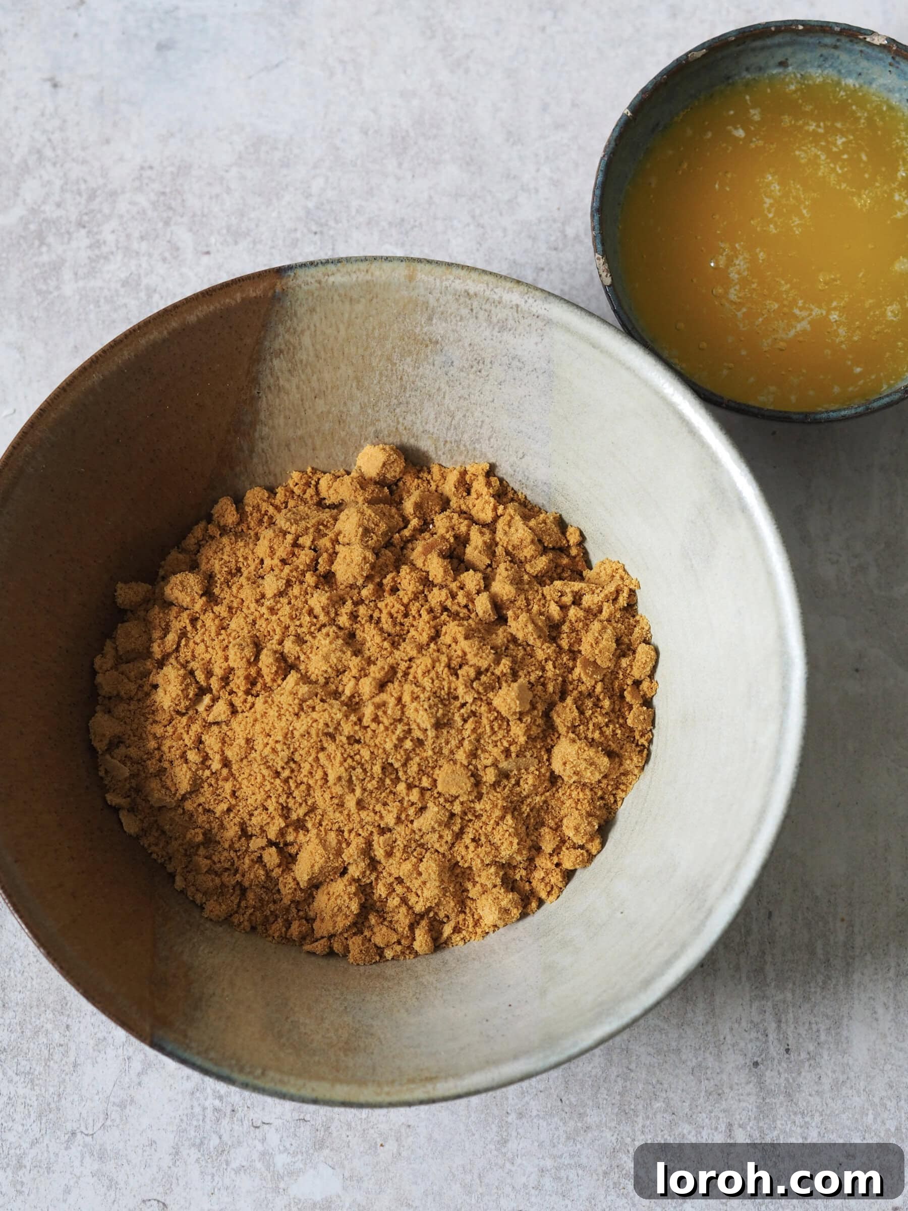 Crushed gingernut biscuits mixed with melted butter, ready to form the cheesecake base.